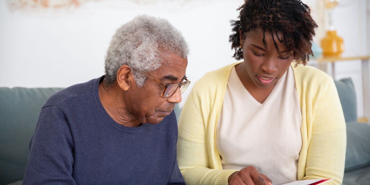 A staff member sitting beside a resident, reading together