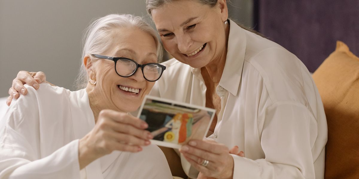 A senior woman smiling while sharing an old photograph